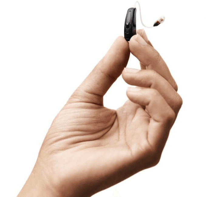 A small hearing aid held between fingertips